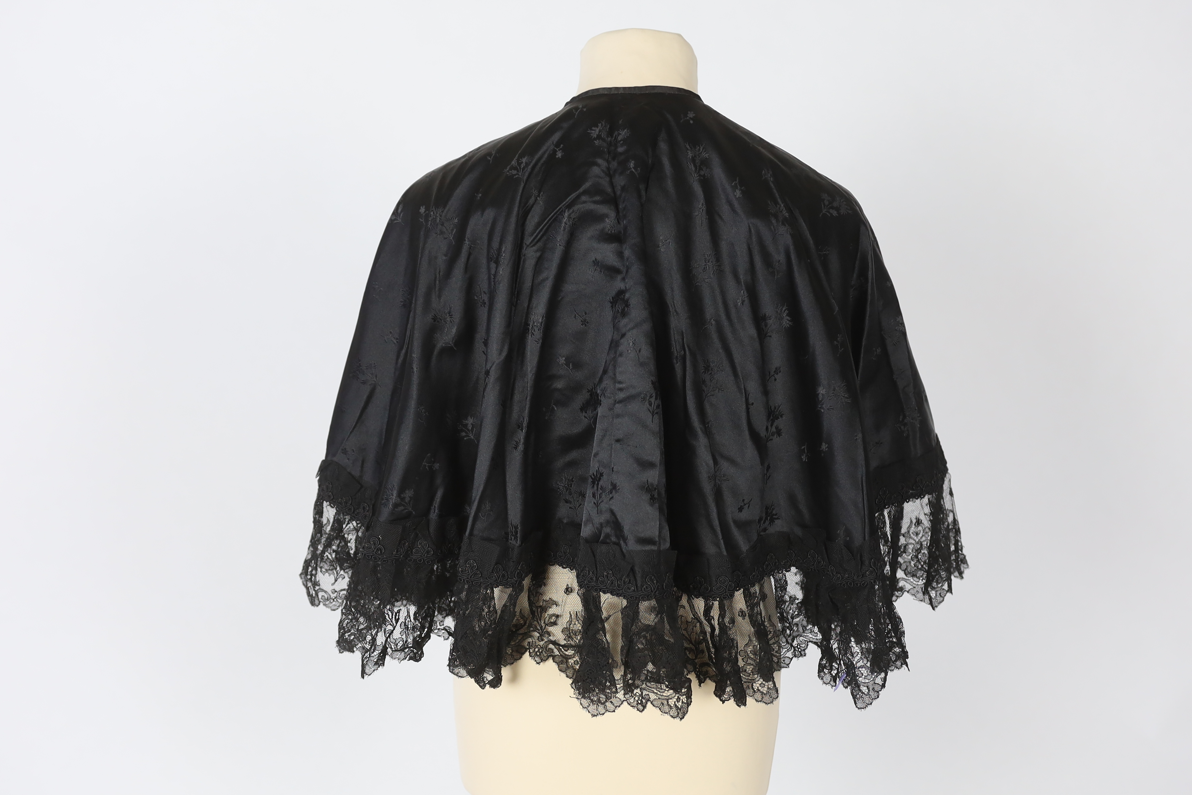 Two lady's Victorian black satin and lace, bead trimmed bodices, together with a black lace cape, a black satin cape, a small collection of coloured feathers and a child’s white worked pinafore